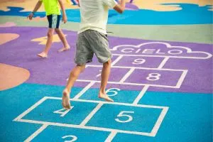 Un enfant qui joue à la marelle dans une cour de récréation.