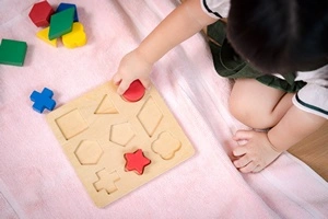 Jeux trieur de formes : une petite fille tente de poser les formes dans les bons emplacements.