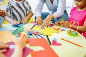 Jeux créatifs : une femme entourée d'enfants fait du coloriage et du découpage.