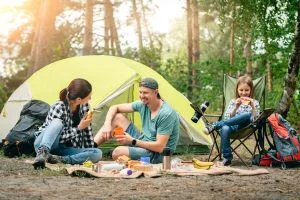 Une famille font du camping. Ils sont autour du feu et discute avec leurs enfants.