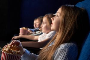 Des enfants qui regardent un film au cinéma. Ils profitent d'une réduction lors des vacances scolaires pour une sortie cinéma pas cher.