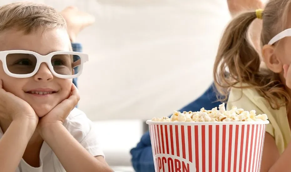 Deux enfants portent des lunettes de cinéma 3D et sourient.