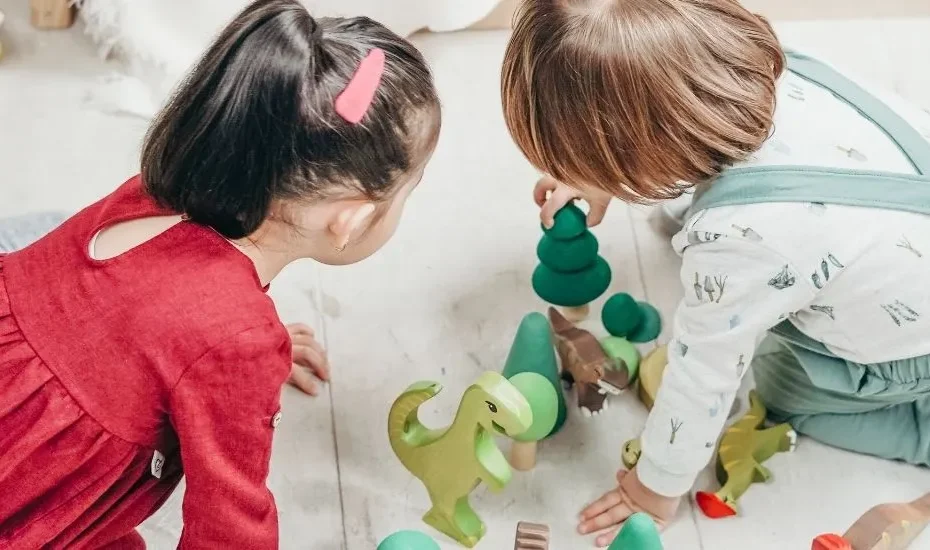 Deux enfants en train de jouer à des jeux en bois sur un tapis.