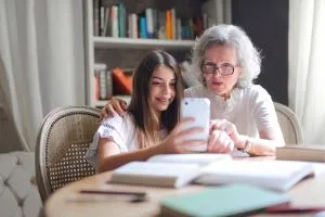 Une mamie avec une jeune qui découvre comment fonctionne un téléphone.