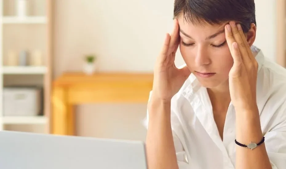 Une femme stressée devant son ordinateur qui se masse les tempes.