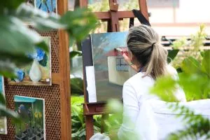 Une femme peint un tableau sur un chevalet en bois