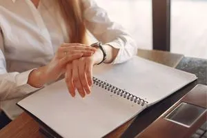 Une jeune femme qui regarde sa montre alors qu'elle travaille ou étudie en signe de stress.