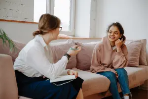 Une psychologue discute avec une jeune femme sur un canapé pour traiter son stress.