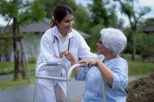 Une jeune infirmière vient en aide à une grand-mère dans un parc.