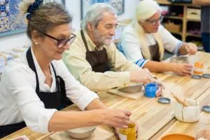 Des seniors qui font de la poterie en groupe.