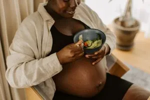 Une femme enceinte qui mange avec plaisir des aliments sains.