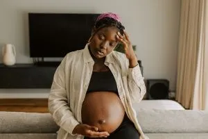 Vitamine D et grossesse : une femme enceinte qui se tient la tête en guise de stress.