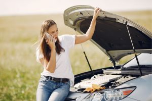 Une femme appelant son assurance auto car elle est en panne sur le bas coté de la route.