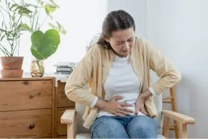 Une femme avec des problèmes de digestion, pose ses mains sur son ventre.