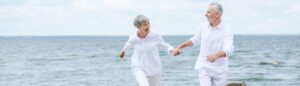 Un couple à la retraite qui court sur une plage heureux.