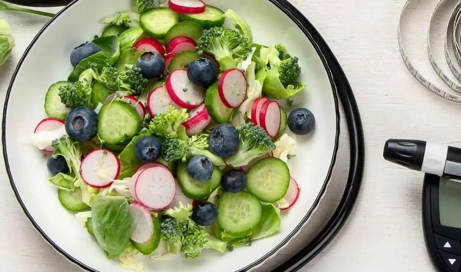 Baisser sa glycémie naturellement : un glucomètre, une salade de radis posés sur une table gris clair.