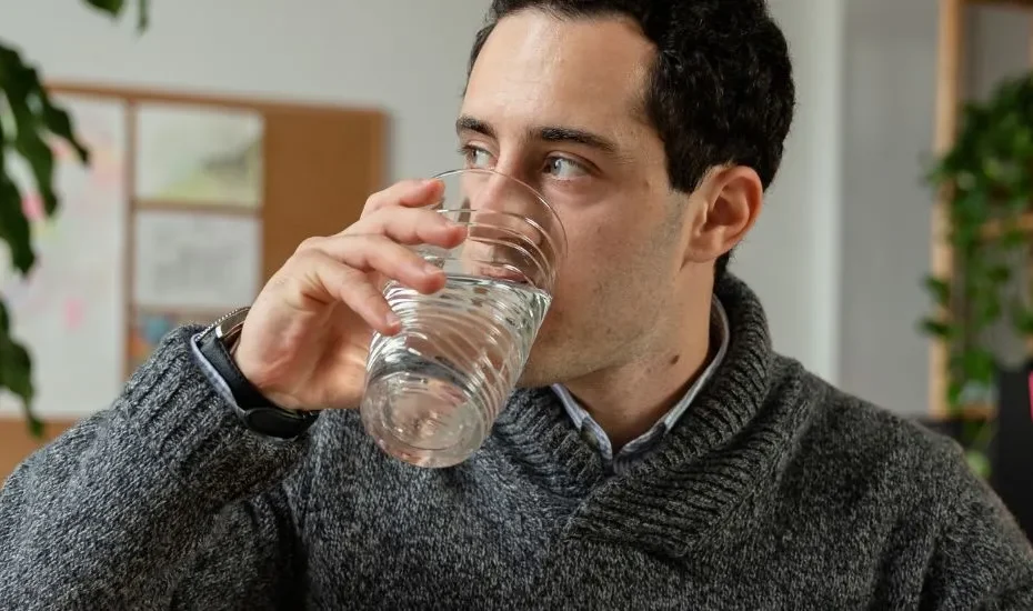 Un homme qui boit de l'eau libre de PFAS dans un verre.