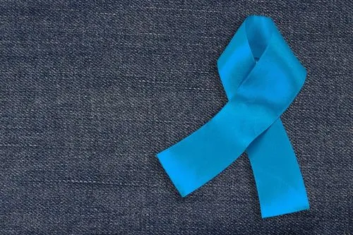 Un ruban bleu en signe de cancer de la prostate posé sur un fond en jeans.