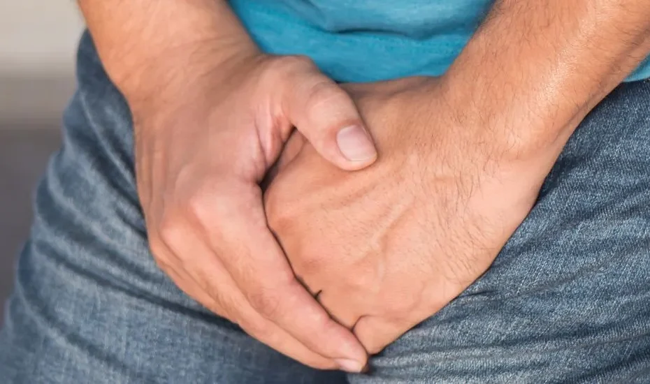 Un homme met ses mains au niveau de la vessie parce qu'il a des problèmes de prostate.