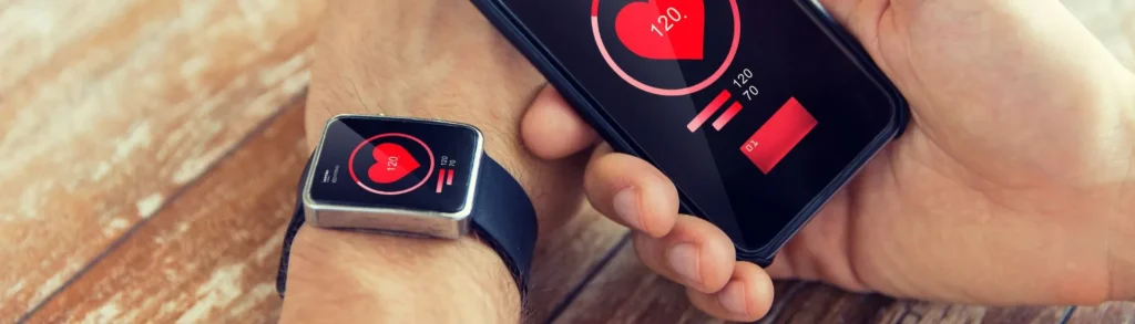 Une smart watch (objet connecté) et un téléphone qui affichent le rythme cardiaque.