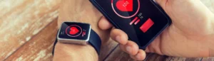 Une smart watch (objet connecté) et un téléphone qui affichent le rythme cardiaque.