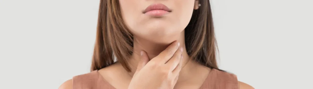 Une femme qui se tient la gorge avec la main car elle souffre de la thyroïde (hyperthyroïdie)