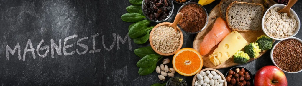 Des aliments riches en magnésium sur une ardoise noire où est écrit le mot magnésium en craie blanche.