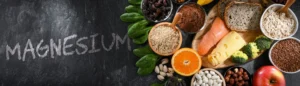 Des aliments riches en magnésium sur une ardoise noire où est écrit le mot magnésium en craie blanche.