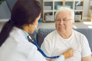 Un senior se fait ausculter le cœur par une médecin.