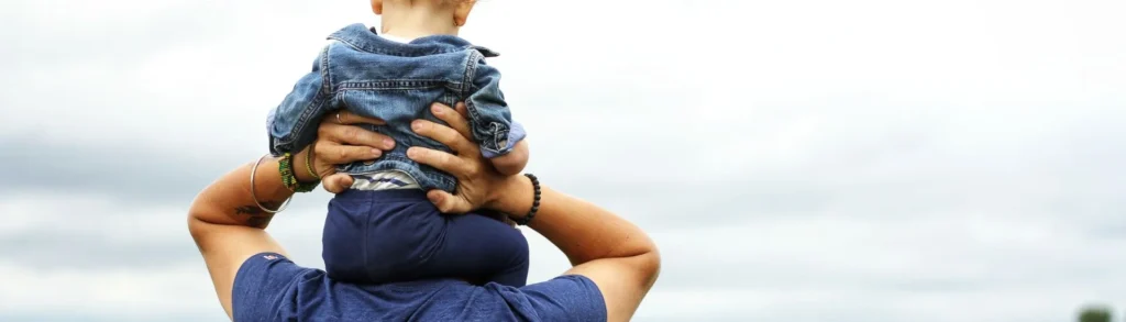 Un enfant assis sur les épaules de son père. Il fait son rôle sur l'éducation.