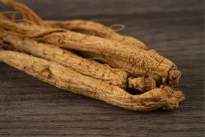 Racines de ginseng en gros plan sur une table en bois, l'une des meilleures solutions naturelles en pharmacie contre les problèmes d’érection.