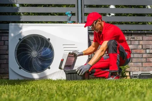 Un ouvrier installe une pompe à chaleur dans le cadre d'une rénovation énergétique.