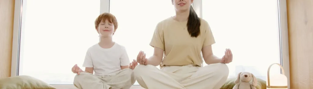 Une maman et son fils font une routine bien-être en pratiquant des exercices de yoga ensemble.