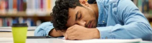 Un jeune étudiant en manque de sommeil qui dort sur sa table à la faculté.