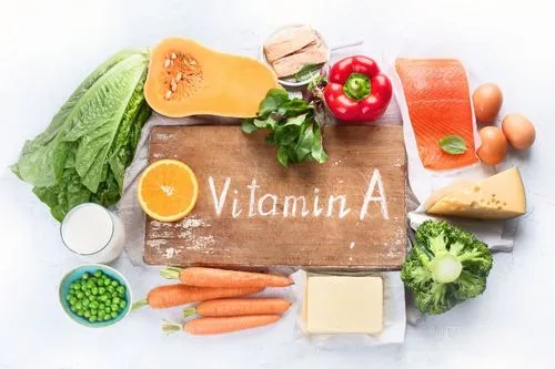 Des aliments riches en vitamine A sur une table : butternut, saumon, carottes, beurre, brocolis, etc.