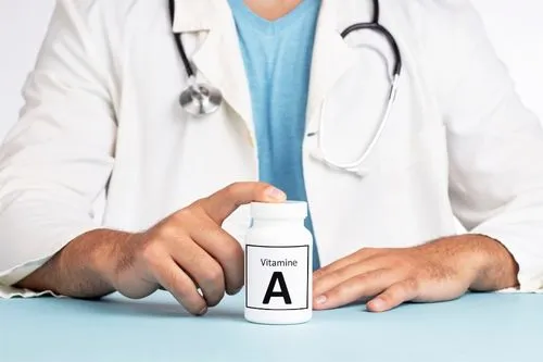 Un médecin pose avec un flacon de vitamine A devant lui.