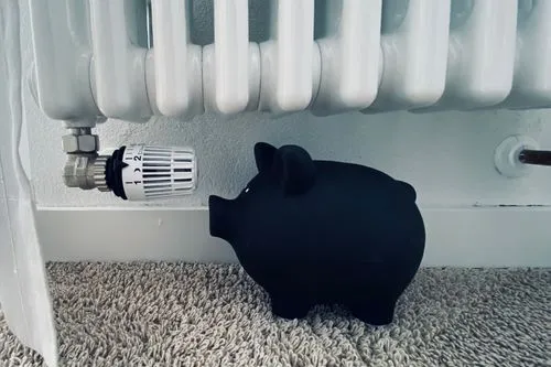 Une tirelire en forme de cochons en dessous d'un radiateur.