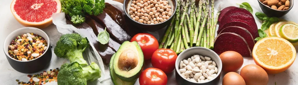 Aliments riches en vitamine B9 sur une table (foie, asperges, fruits, légumineuses, légumes verts).