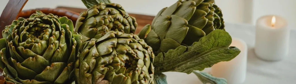 Des artichauts riches en bienfaits posés dans un panier à côté d'une bougie.