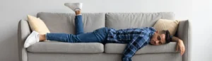 Un homme couché sur un canapé. Il est épuisé car il souffre d'une baisse de la testostérone.