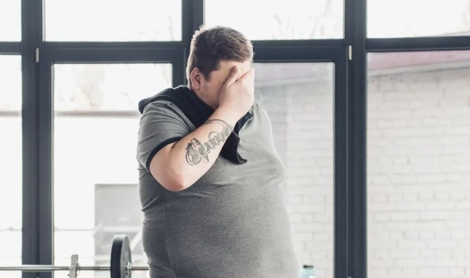 Un homme en surpoids souffre d'hypogonadisme. Il est épuisé dans une salle de sport.