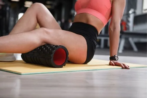Une femme qui favorise la récupération musculaire grâce à un foam roller.