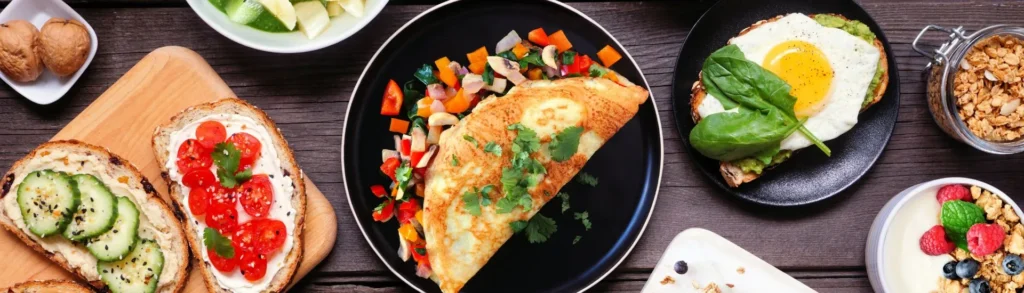 Photos de plats pour un menu régime hyperprotéiné. On aperçoit une omelette au poulet et aux légumes, des tartines, etc. sur une table.