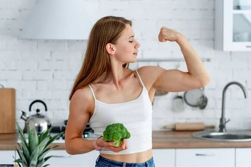 Une femme végétarienne qui a des muscles et contracte son biceps.