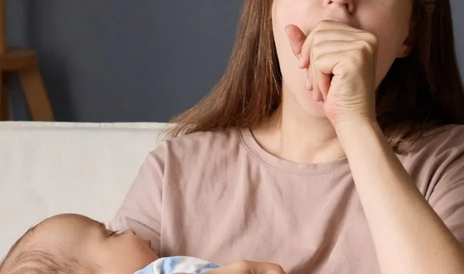 Une jeune maman baille proie à la fatigue avec son bébé dans les bras.