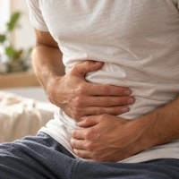 Une homme qui se tient le ventre en signe de problème de digestion.